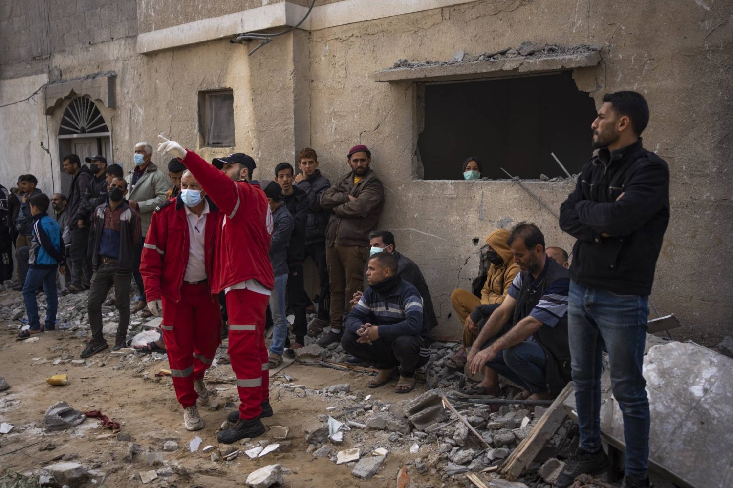 فلسطينيون وعناصر من الهلال الأحمر الفلسطيني يبحثون عن جثث في منزل أصيب بغارة إسرائيلية في رفح بقطاع غزة (أ.ب)