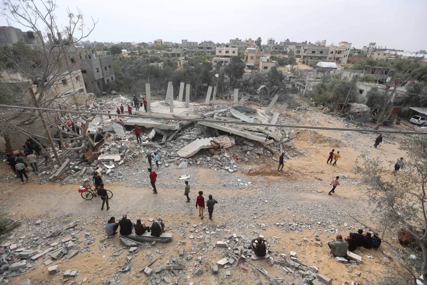 فلسطينيون يتفقدون موقع غارة إسرائيلية على منزل في خان يونس (رويترز)