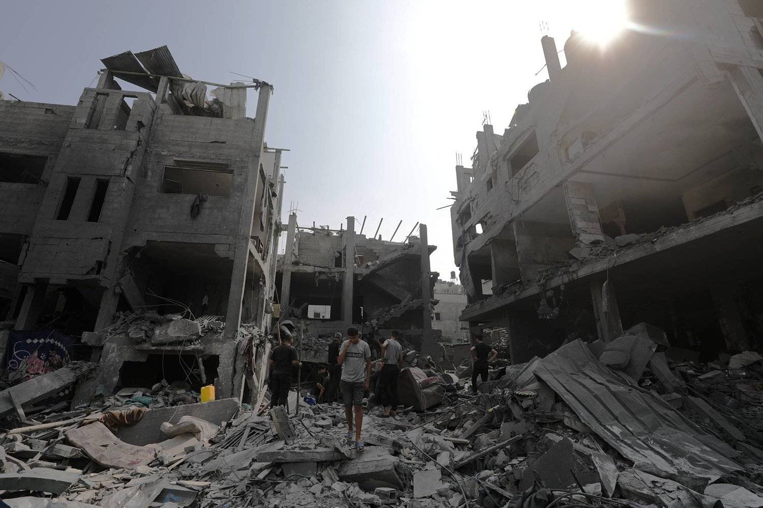 فلسطينيون وسط الدمار جراء القصف الإسرائيلي على غزة (إ.ب.أ)
