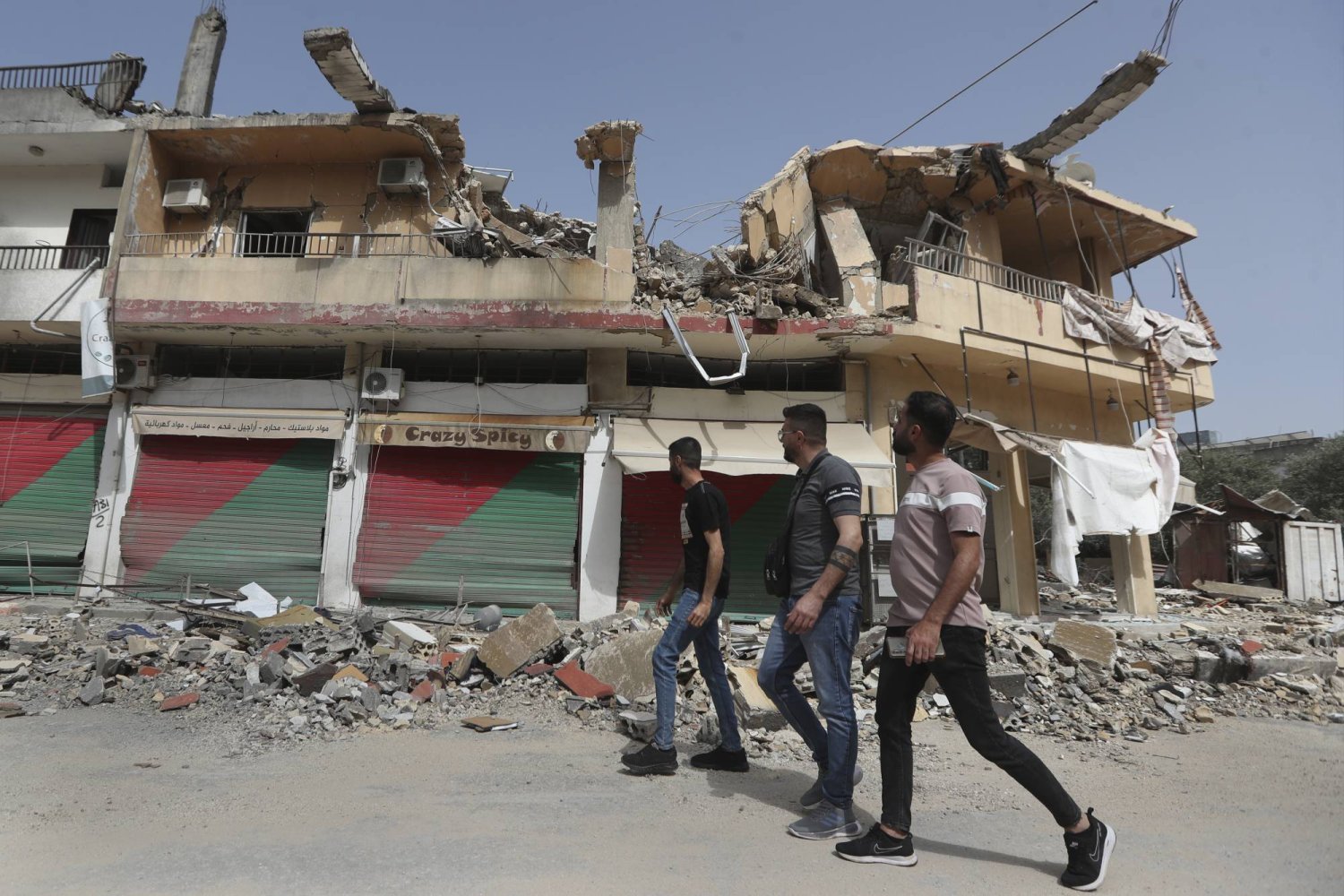 مواطنون لبنانيون يمرّون أمام مبنى مدمّر نتيجة القصف الإسرائيلي في بلدة كفركلا بجنوب لبنان (أ.ب)
