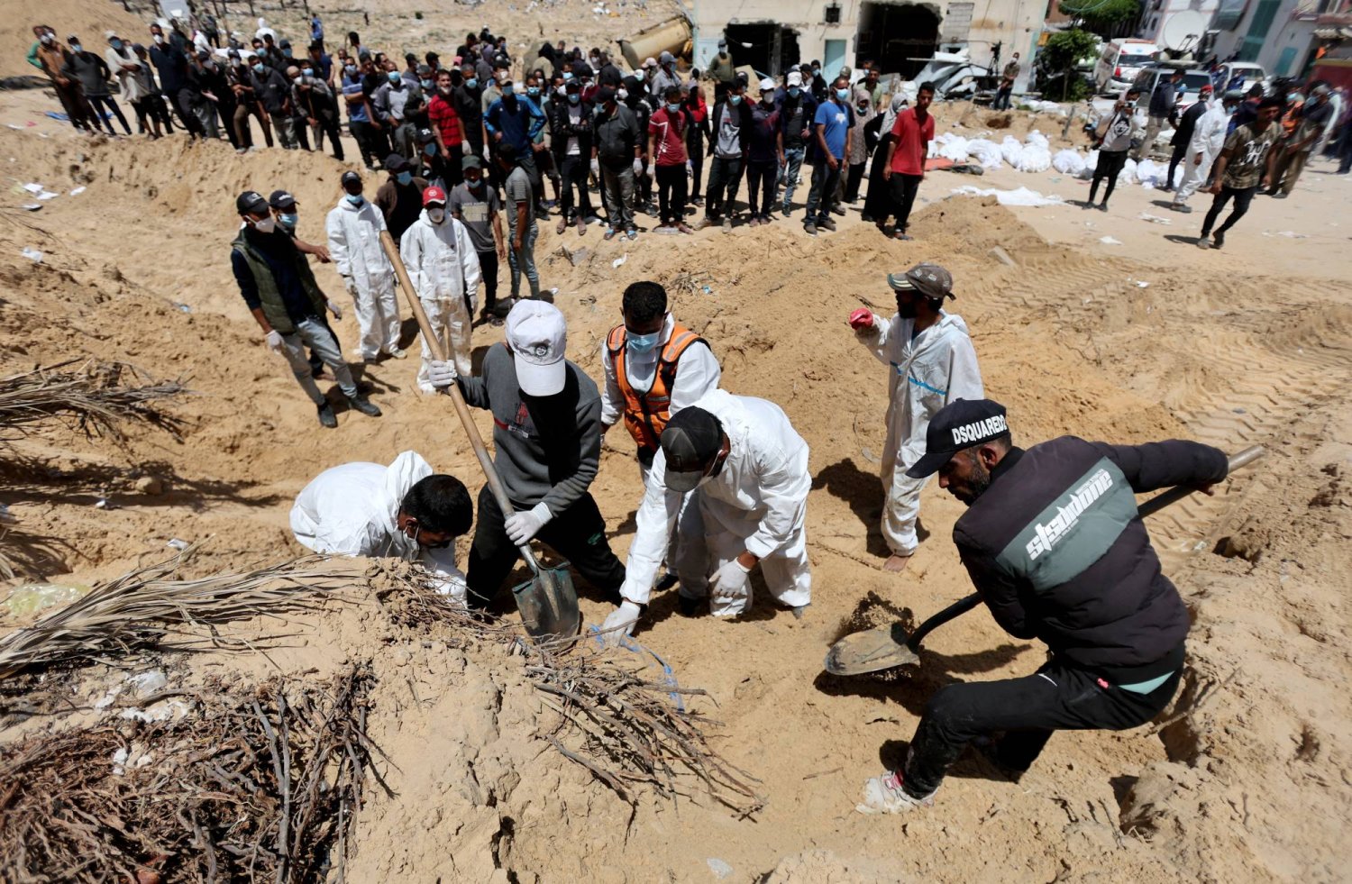 أشخاص يعملون على نقل جثث الفلسطينيين الذين قتلوا خلال الهجوم العسكري الإسرائيلي ودفنوا في مستشفى ناصر في خان يونس جنوب غزة (رويترز)