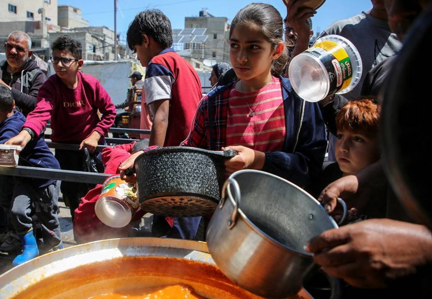  Palestinians gather to receive food cooked by a charity kitchen, amid shortages of aid supplies, after Israeli forces launched a ground and air operation in the eastern part of Rafah, as the ongoing conflict between Israel and Hamas continues, in Rafah, in the southern Gaza Strip May 8, 2024. (Reuters)